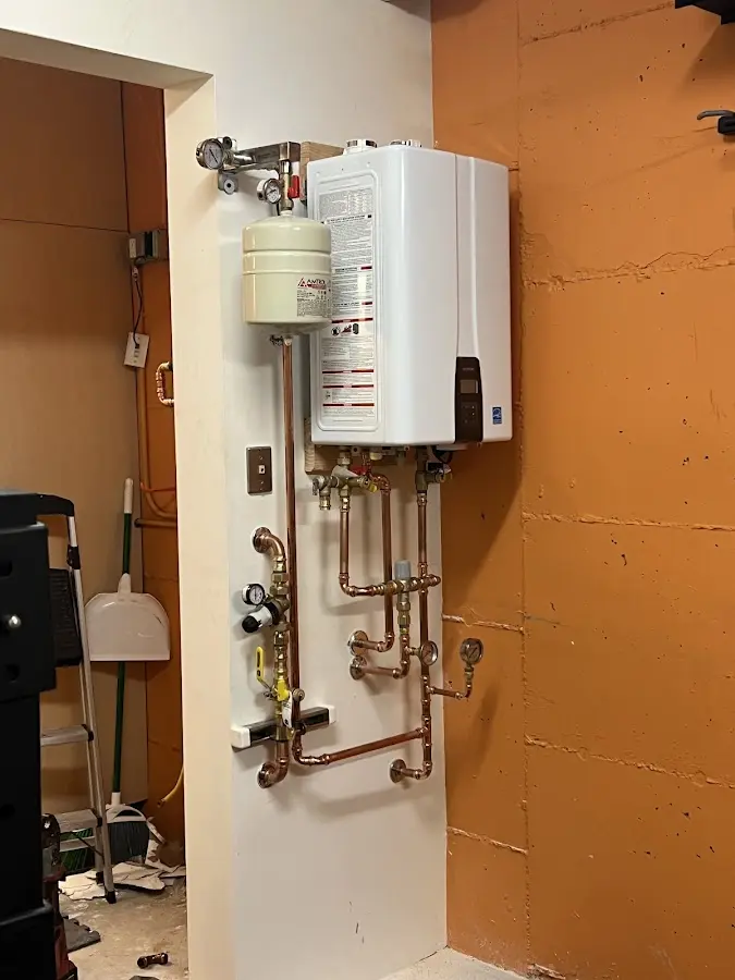Plumbing technician inspecting water heater connections in Champlin